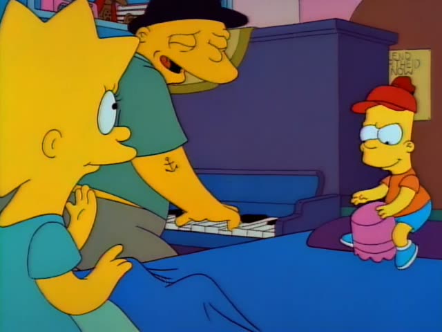 Lisa sits in the left foreground beside a man in a black hat and green shirt with an anchor tattoo on his forearm, who plays…