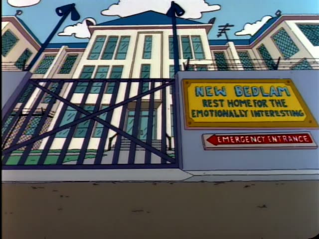 Homer reclines on a couch in a pink shirt and blue trousers while Mr. Burns sits in a white coat holding up an inkblot card…