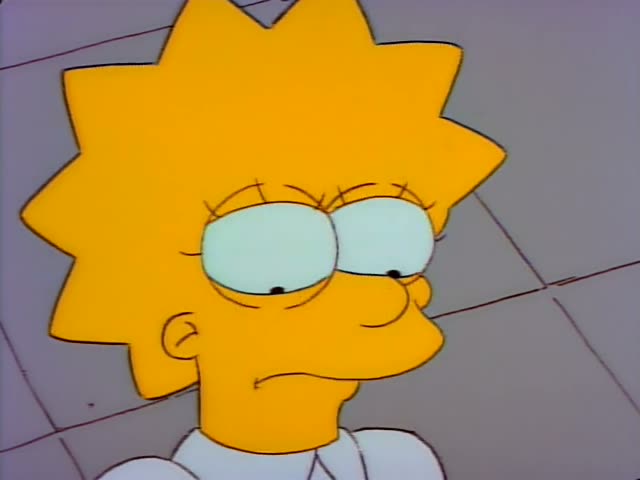 Lisa first looks glum and then grimaces and speaks with her mouth open in a close-up against a grey tiled wall