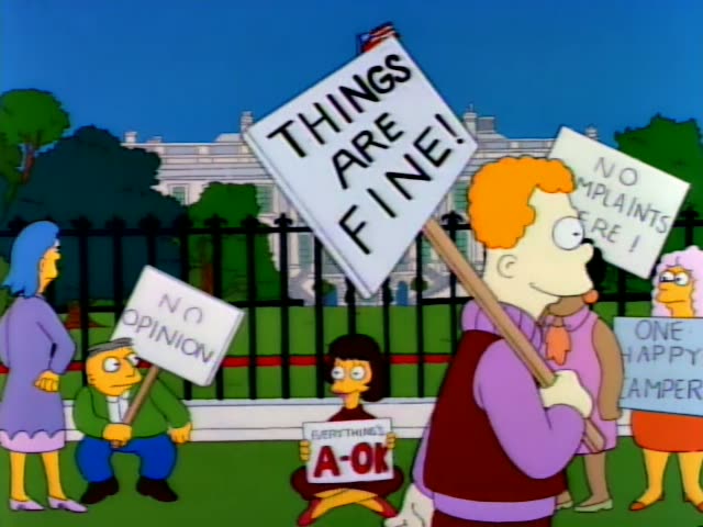 Protesters with signs reading "Things Are Fine!", "No Opinion", "No Complaints Here", "One Happy Camper"…