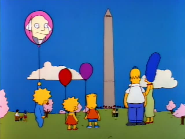 Homer and Marge stand in a park with Lisa, Bart, and a small child in blue holding a pink face-shaped balloon, facing a tall…
