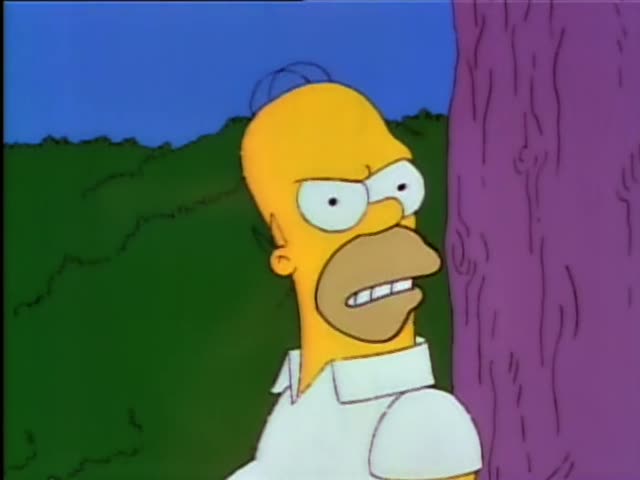 Homer Simpson peeks out from behind a large purple tree trunk against a green hedge and blue sky