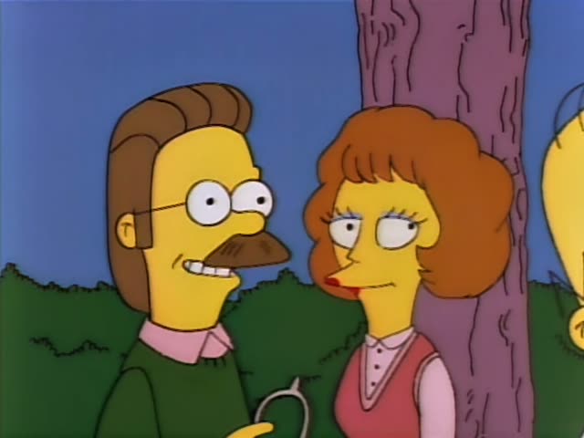 Ned Flanders and a woman with a big auburn hairdo in a pink vest stand under a tree on a grassy lawn, with Ned…