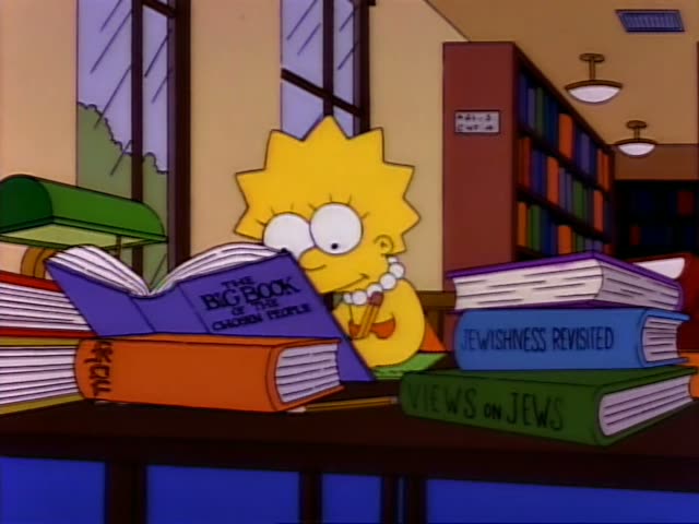 Bart sits at a library table in the foreground, leaning over a large open picture book while Lisa reads a book nearby…