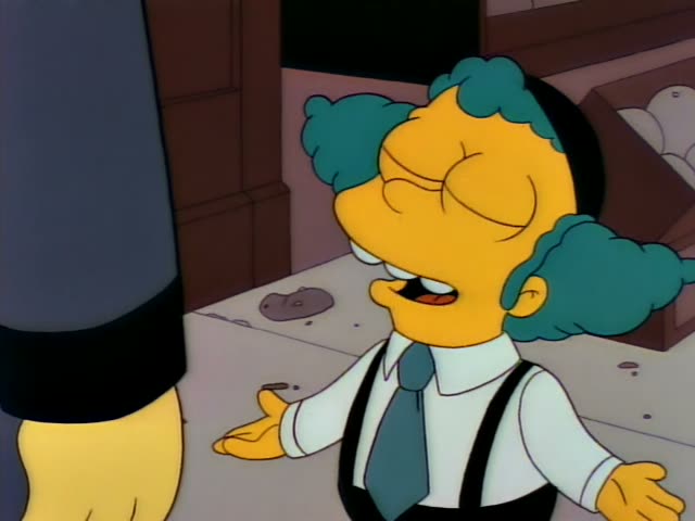 A teal-haired, round-faced character with a black hat, white shirt, tie and suspenders stands at the left of a street-side…