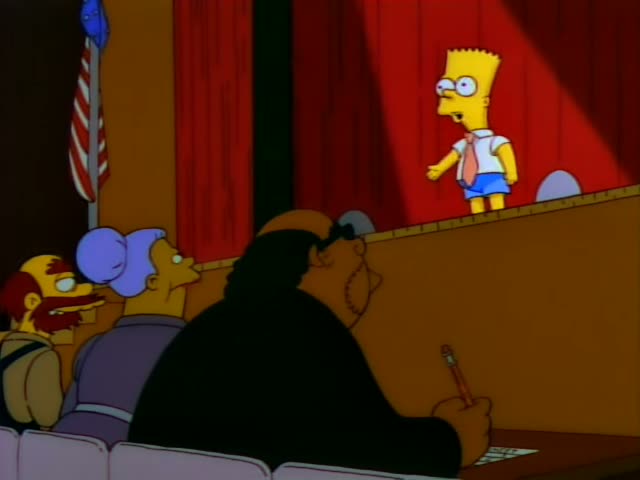 Bart stands on a red-curtained stage gesturing with one hand while audience members in the foreground watch: a heavy man…