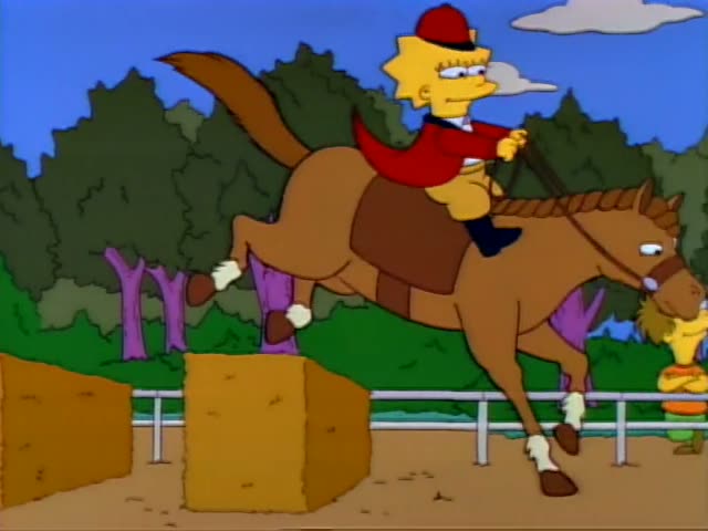 Lisa rides a brown horse over a hay bale on a sandy track while Bart in an orange shirt, a boy with glasses in an orange…