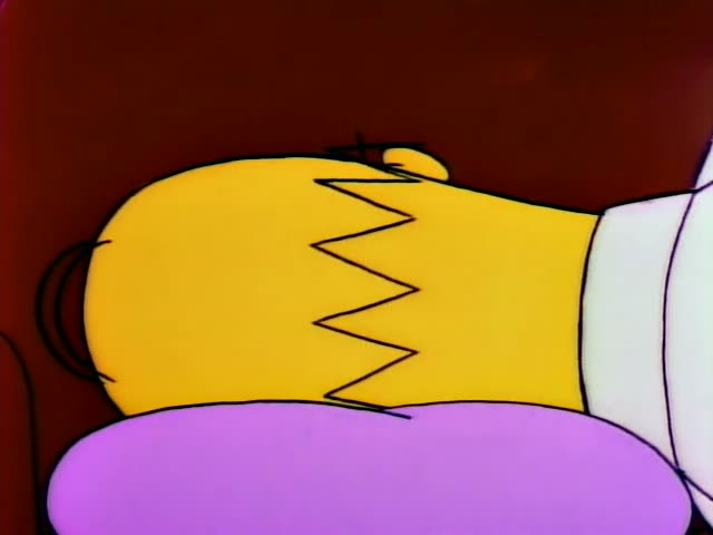 Homer Simpson first appears in a close-up with his yellow head resting on a purple cushion, then lies face down on the brown…