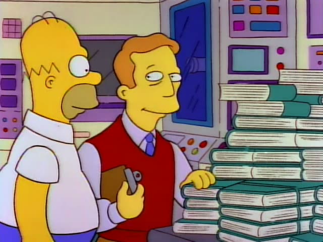 Troy McClure stands at a counter stacked with green-spined books, holding a clipboard and pen while resting a hand…