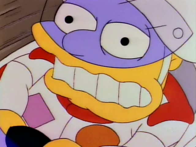 A stunt performer with a purple face, huge teeth and a white helmet, wearing a white jumpsuit with red trim, rides a white…
