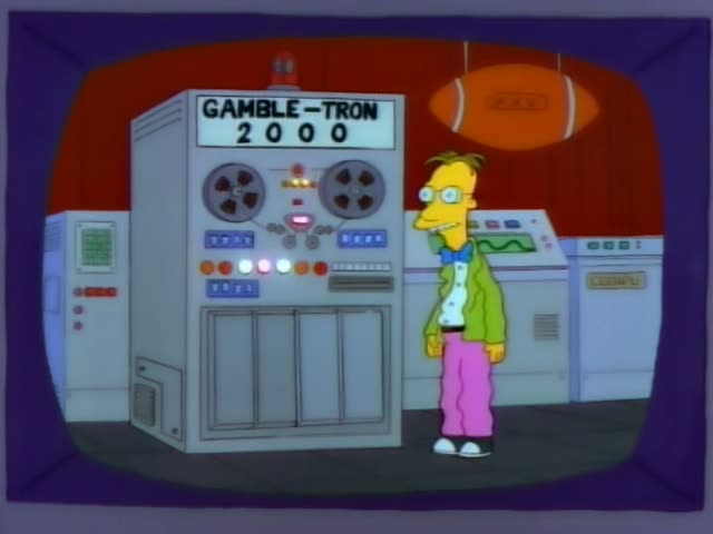 A thin, bespectacled man with a blue bow tie, green jacket and pink trousers stands beside the Gamble-Tron 2000 machine…