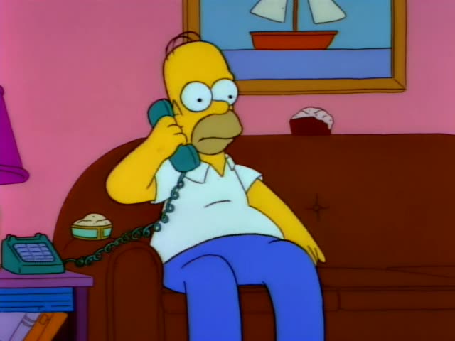 Homer Simpson sits on the edge of a brown couch in a pink living room, holding a teal phone to his ear with its cord…
