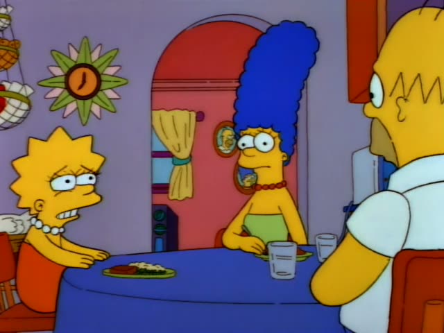 Lisa sits at a blue-covered dinner table beside Marge, whose tall blue beehive and red beads are visible, while Homer's bald…