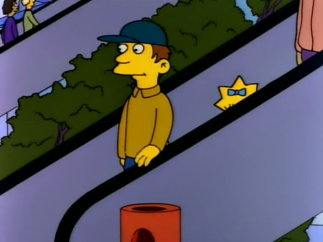 Maggie starts near an escalator where a man in a teal cap and mustard-yellow shirt rides beside a potted hedge…