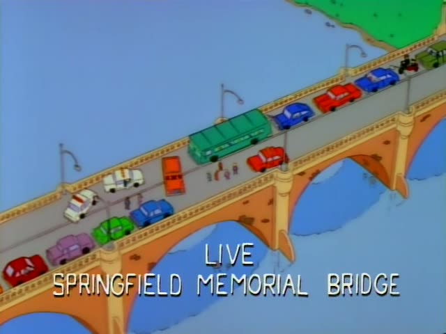Marge Simpson sits in a red car stalled in a jammed line of traffic on the Springfield Memorial Bridge, while a reporter…