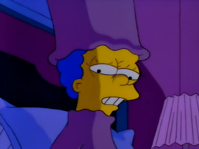 Marge lies in bed beside Homer, who is bald and wears a light blue shirt, in a dim bedroom with purple walls