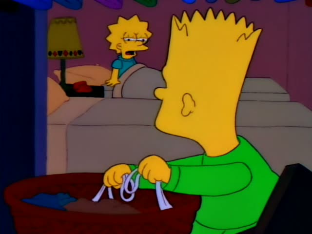 A spiky-haired boy in a green shirt crouches beside a red wicker basket in a bedroom, lifting white cup-shaped garments…