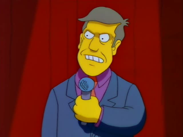 Principal Skinner stands before a red curtain holding a microphone
