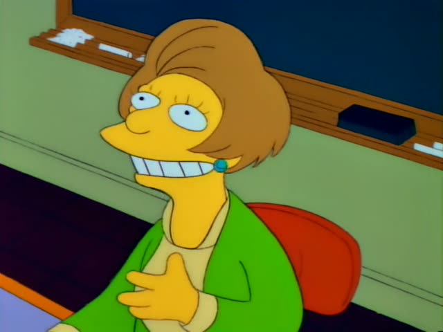 Bart is in a classroom with Mrs. Krabappel, who has a brown hairdo and a green cardigan and grins at the desk, while a woman…