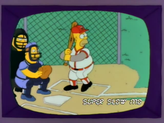 Homer stands at home plate in a ballpark with a chain-link backstop while a catcher in blue gear crouches behind him…