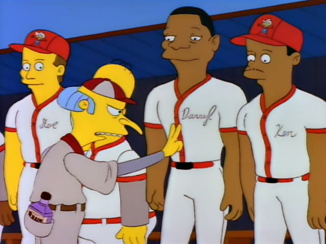 Mr. Burns wears a red-and-white cap and a grey Zephyrs uniform on a baseball field, first holding up a purple bottle…