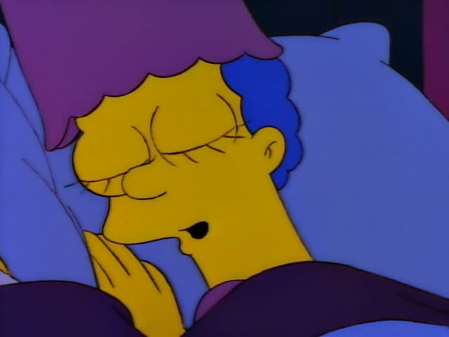 Marge Simpson lies in bed under purple covers, her eyes wide and a small smile on her face, with a hand near her chin