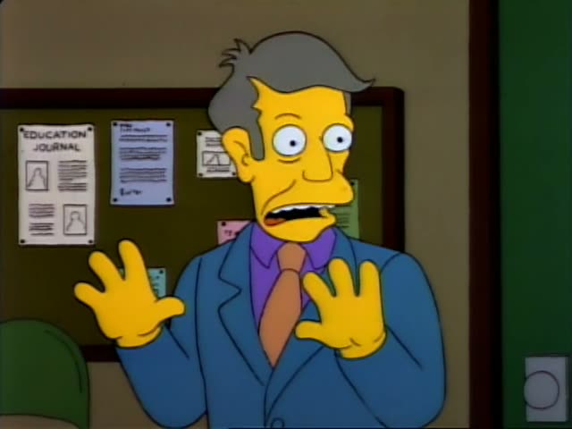 Principal Skinner first stands gesturing with both hands in front of an Education Journal bulletin board, then turns to peer…