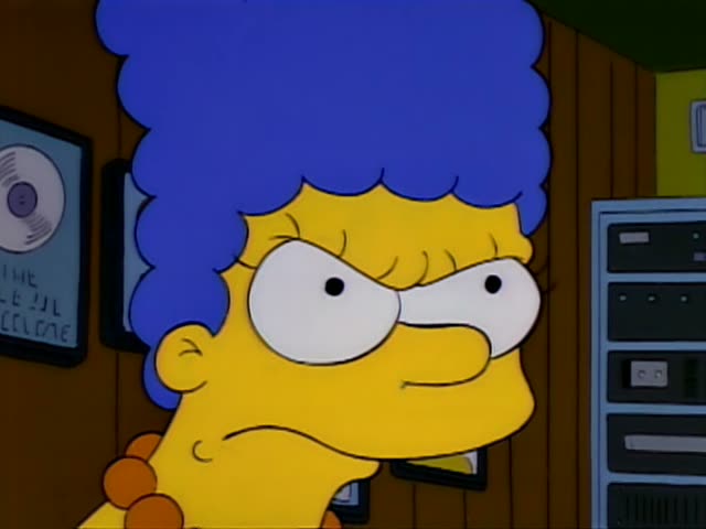 Marge Simpson glares and then grits her teeth in anger, and the scene shifts to a radio booth behind glass where Homer…