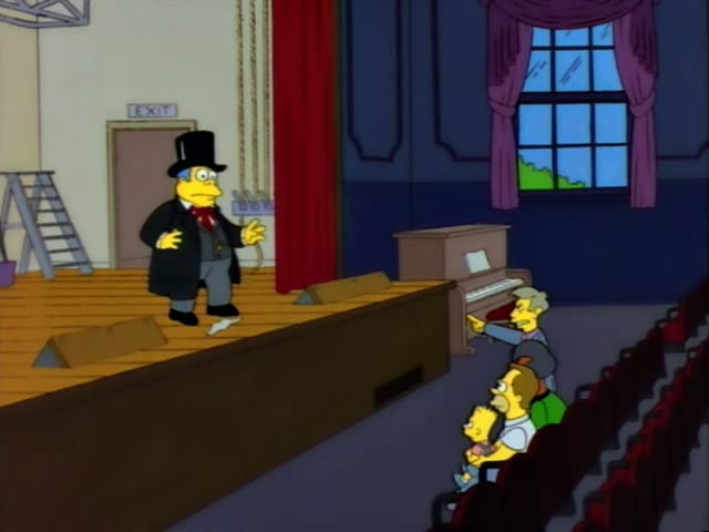 Homer and Bart sit in a theater audience with an elderly man with white tufts of hair beside them, while a man in a top hat…