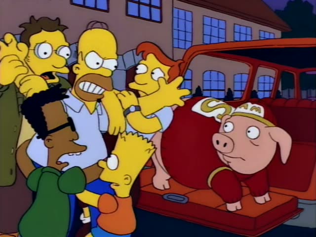 Homer yells and reaches toward a plump pig in a red outfit and cap, sitting on the open trunk of a red car outside a brick…