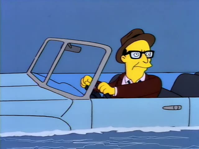 A bespectacled man in a brown fedora and maroon jacket drives a light blue car through a stream, grinning, gesturing…