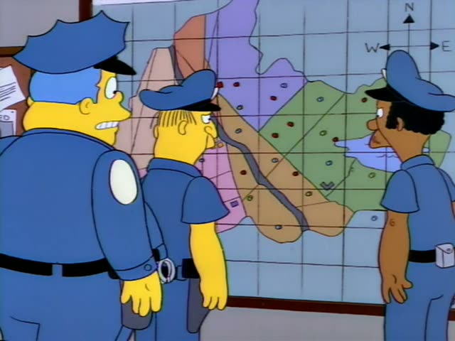 Chief Wiggum stands in front with a thin, yellow-skinned officer in a cap beside him, while a dark-skinned officer in a cap…