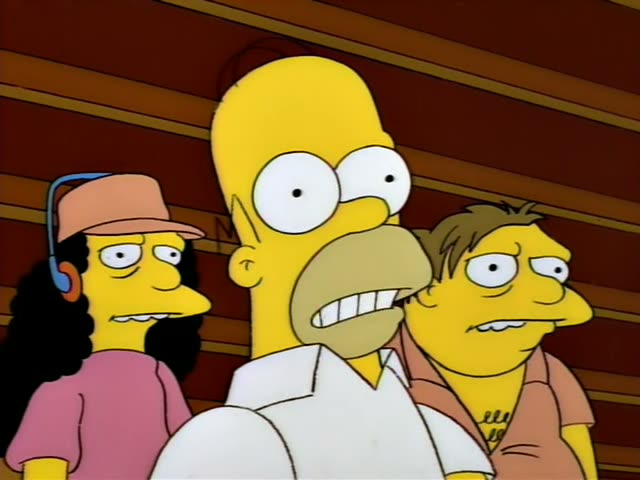 Homer stands in the center with his mouth open, flanked by Otto in a pink cap and headphones with long curly black hair…
