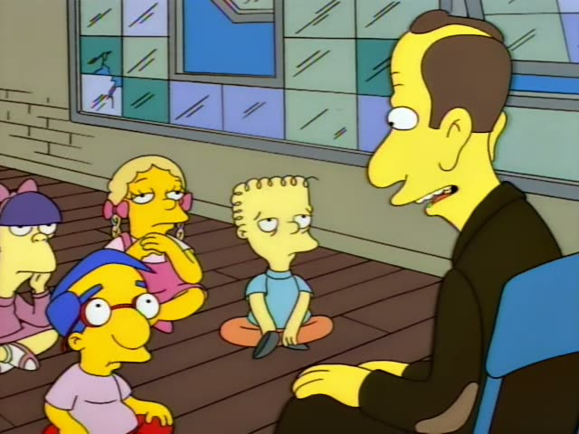 Bart Simpson in his orange shirt and blue shorts sits cross-legged on a wooden floor beside Milhouse in a blue cap…