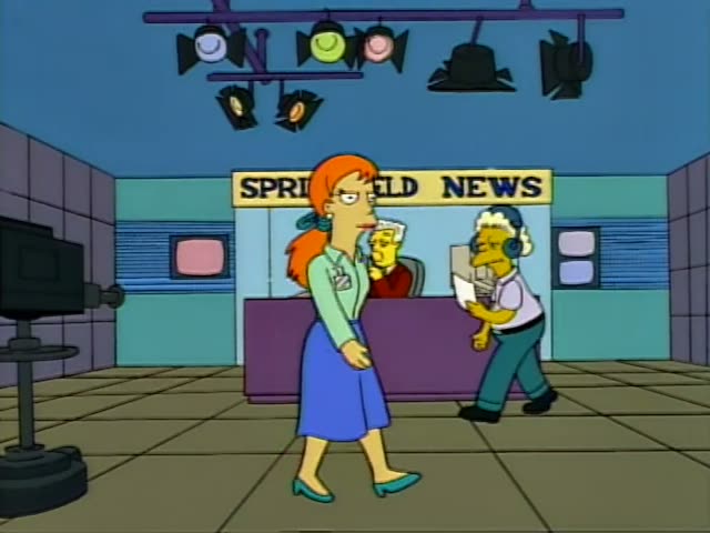 Kent Brockman sits behind a purple desk marked Springfield News while an unnamed woman with an orange ponytail, mint…