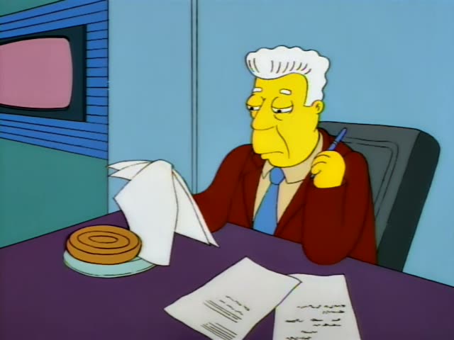 An older man with neat white-grey hair, a dark red jacket and a blue tie sits at a purple desk beside a plate…