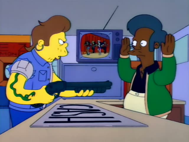 Apu raises both hands beside his head while a young yellow-skinned man with swept-back brown hair, a blue shirt and a green…