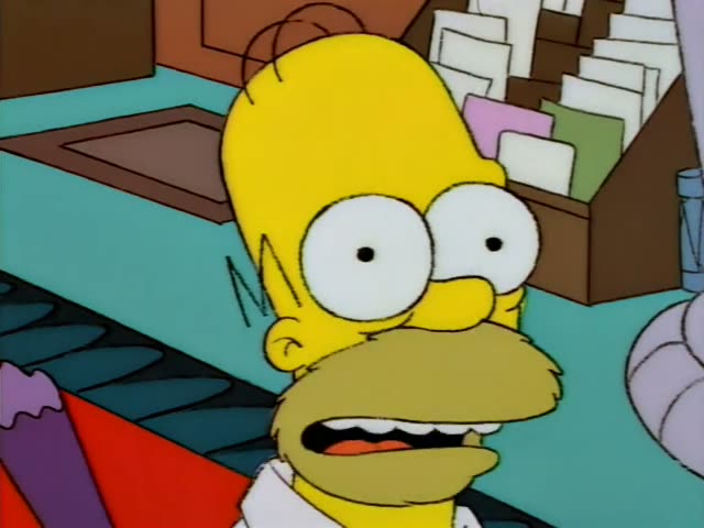 Homer Simpson sits at a teal desk beside a wooden organizer stuffed with folders, his mouth open and eyes wide in surprise
