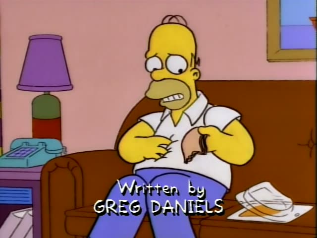 Homer Simpson sits on a brown couch in the living room beside a purple lamp and a turquoise phone, gripping his belly…