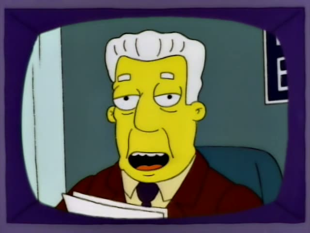 A grey-haired man in a red jacket, white shirt and dark tie, who may be Kent Brockman, sits at a desk on a small purple…