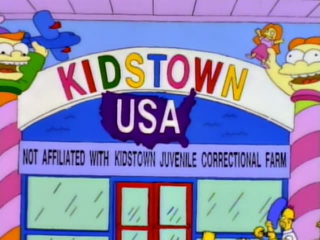 Homer and Marge stand at the entrance of Kidstown USA, a storefront with a sign…