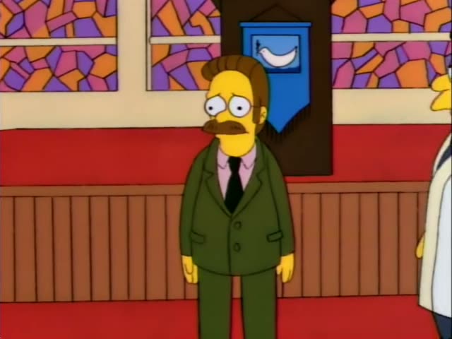 Ned Flanders stands in a church-like hall beside Homer in a blue suit and green tie, and a thin man in a white robe…