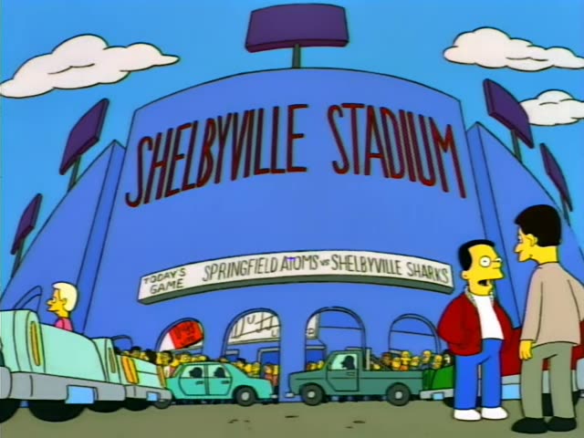 Homer in a white shirt and Ned Flanders in a green sweater, with a small boy in a blue cap, lean over the railing…