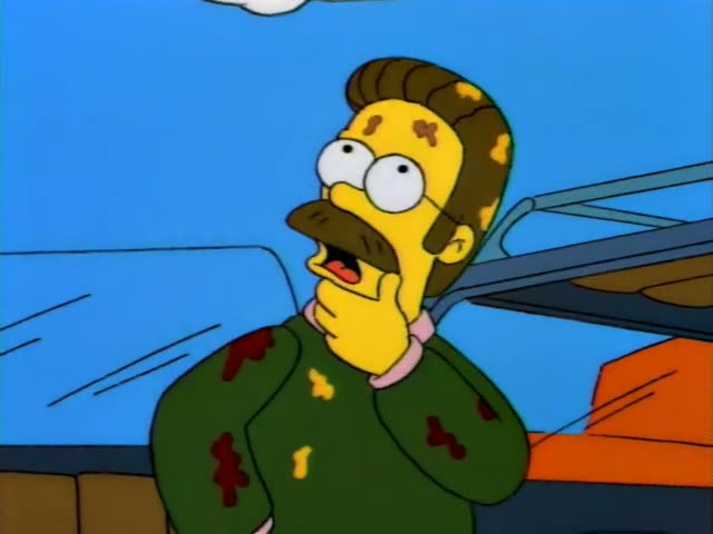 Homer Simpson and Ned Flanders stand together outdoors beside a red camper van and a tan van under a blue sky