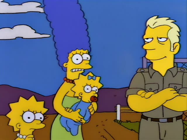 Lisa, Marge and Maggie stand outdoors on a dirt patch under a blue sky with clouds and purple hills, while a man in a khaki…