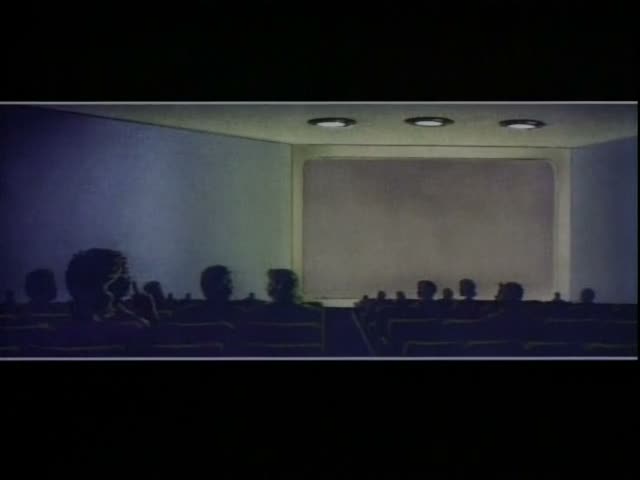 Silhouetted audience members, including a large-haired figure in the foreground, sit in a dark theater facing a blank screen…