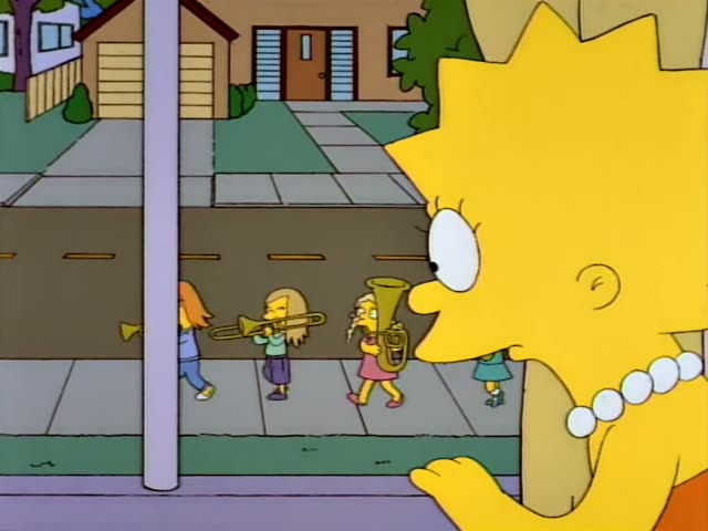Lisa watches from the foreground as a line of children in a marching band passes along a suburban street: a red-haired girl…