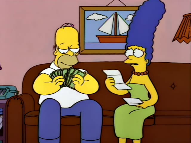 Homer Simpson and Marge Simpson sit side by side on the brown couch in the living room, with a framed sailboat picture…