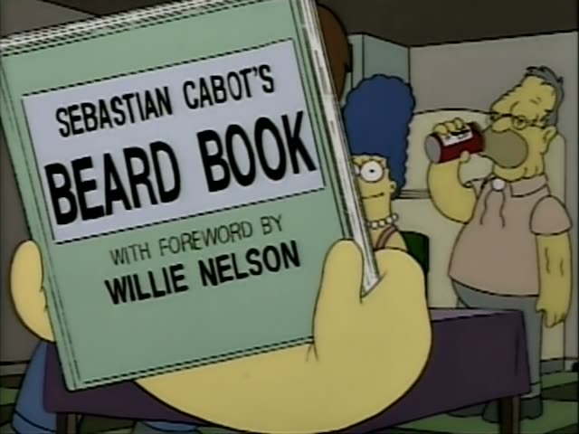 In a kitchen, Marge with her tall blue beehive and Grampa watch a heavy bearded man with brown hair in an orange sleeveless…