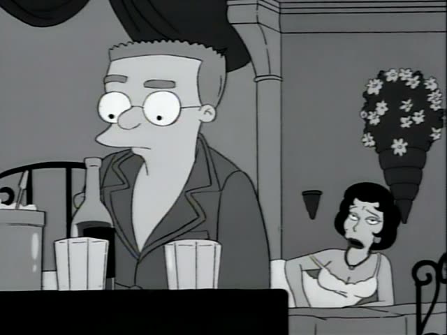 Mr. Burns stands at a dark table in a black-and-white room, wearing a dark jacket over a white shirt